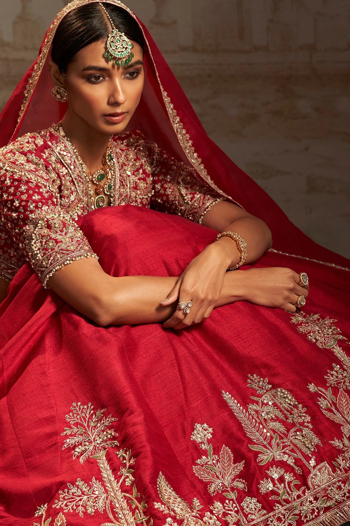 Close-up of gold-tone floral embroidery on a crimson red lehenga and matching blouse